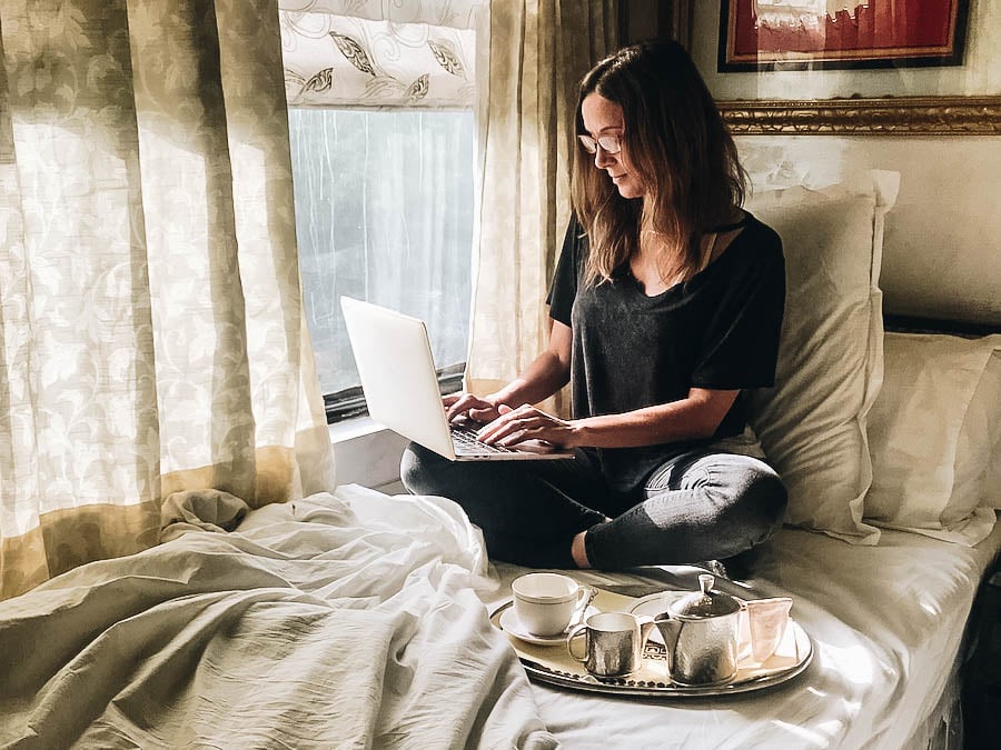 Annette seating beside a window creating a blog on her laptop